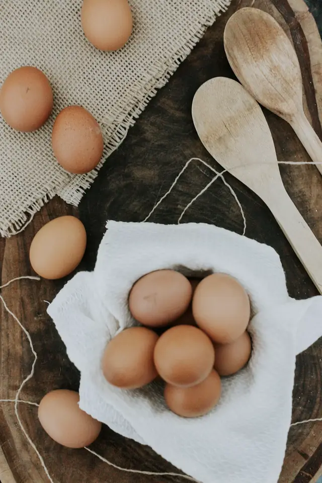 Ovos castanhos num pano branco, com colheres de pau
